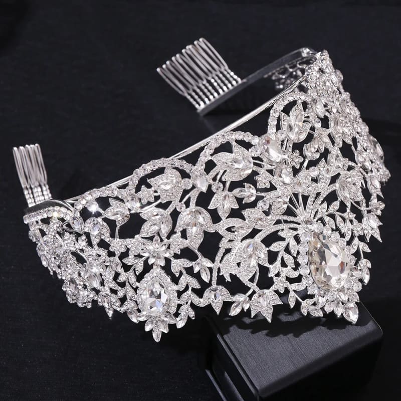 Ornate silver tiara adorned with intricate floral and leaf designs set with sparkling gemstones.
