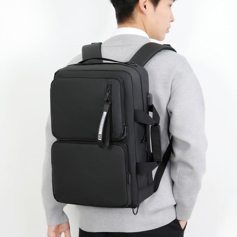 Black backpack with multiple compartments worn by a person.