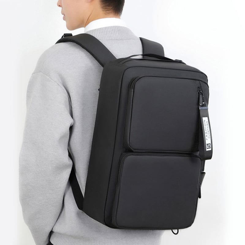 Black rectangular backpack with multiple compartments worn by a person.