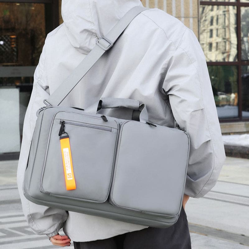 Gray laptop bag with multiple compartments and an orange tag.