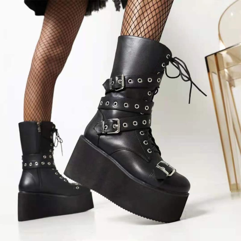Black platform boots with buckles, laces, and metal eyelets worn with fishnet stockings.