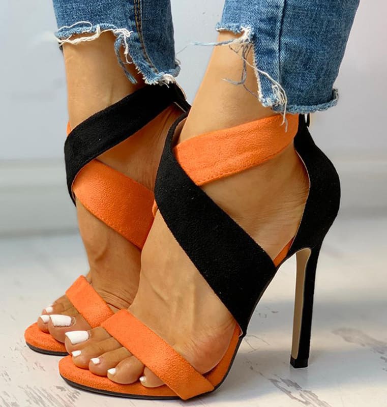 Stylish high-heeled sandals with orange and black straps crossing the foot.