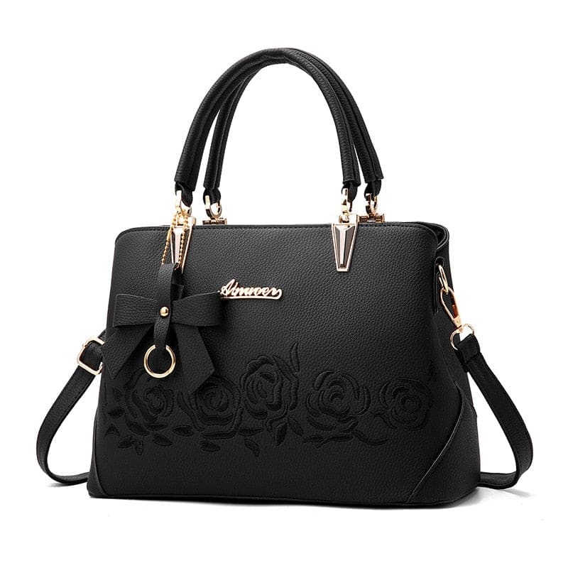Black leather handbag with embossed floral design and gold-tone hardware.