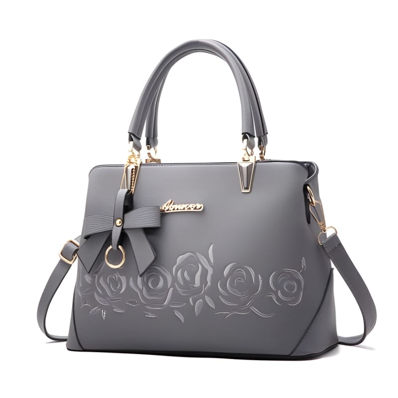 Gray leather handbag with embossed rose design and gold-tone hardware.