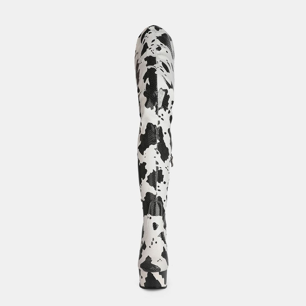 Black and white splatter-patterned rolling pin with Cow Print Thigh Length Platform Boots.