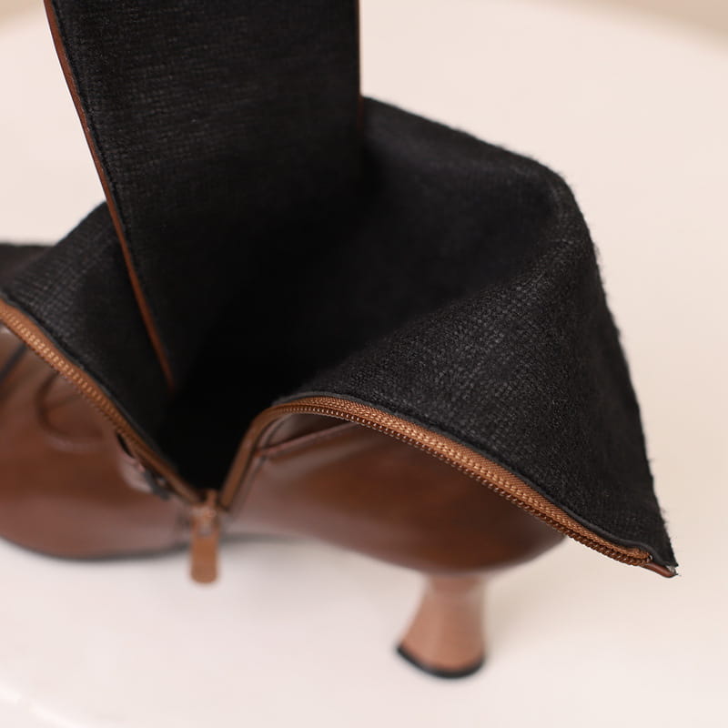 Stilvolle Damen-Stiefeletten mit mittelhohem Absatz und mehreren Schnallen, aus braunem Leder und schwarzem Stoff.