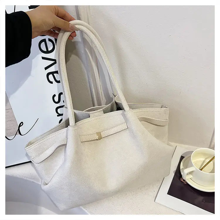White leather handbag with double handles and belt detail for an elegant suede tote.