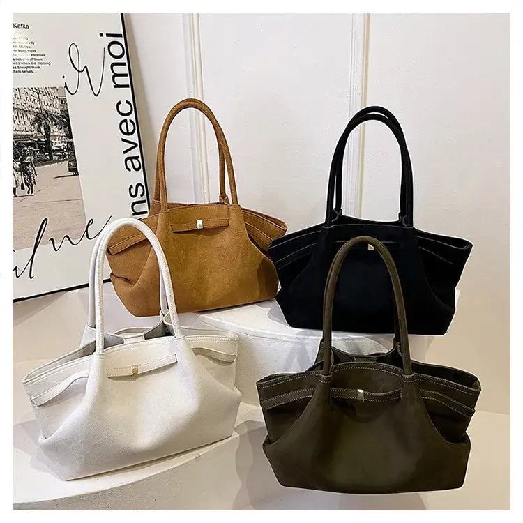 Four stylish suede tote bags in brown, black, white, and olive with curved handles.