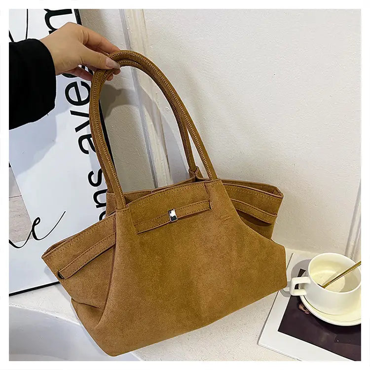Tan suede tote bag with double handles and snap closure, perfect for modern women.