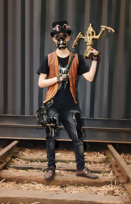 Person in steampunk-inspired attire holding a mechanical puppet or figurine.