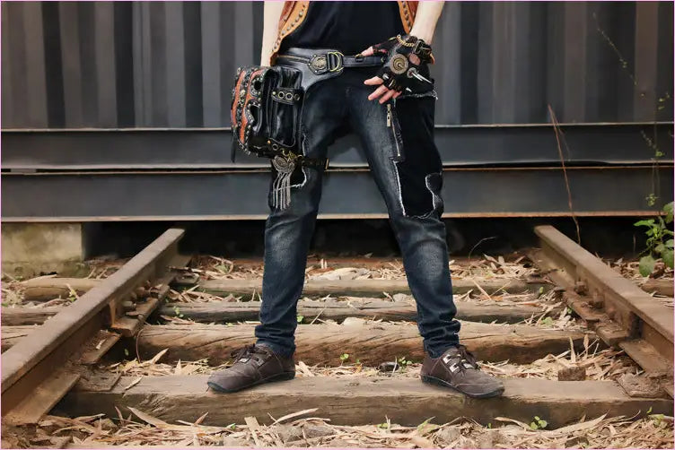 Person wearing jeans and a tool belt standing on railroad tracks.