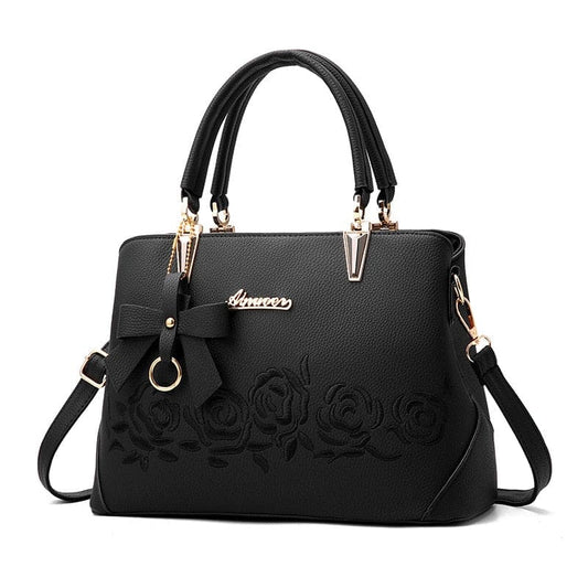 Black leather handbag with embossed floral design and gold-tone hardware.