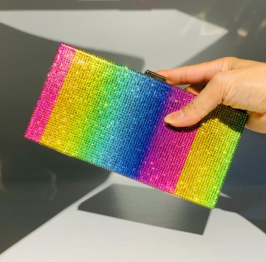 Rainbow-colored sequined clutch purse held by a hand.